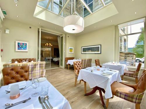 un ristorante con tavoli e sedie e un soffitto in vetro di Knockendarroch Hotel a Pitlochry