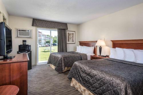 um quarto de hotel com duas camas e uma televisão em Travelodge by Wyndham Gananoque em Gananoque