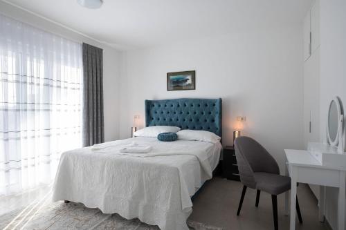 een slaapkamer met een bed met een blauw hoofdeinde en een bureau bij Vila Marta s grijanim bazenom, Sukošan in Sukošan