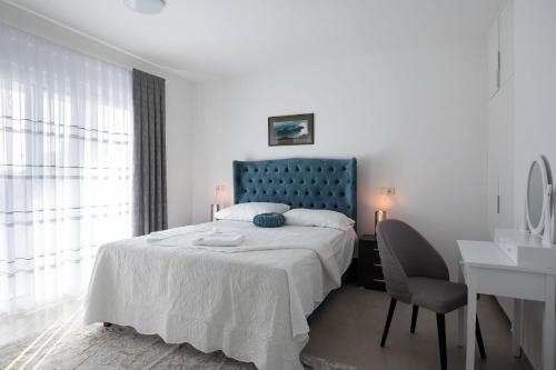 a bedroom with a bed with a blue headboard and a desk at Villa Marta in Sukošan