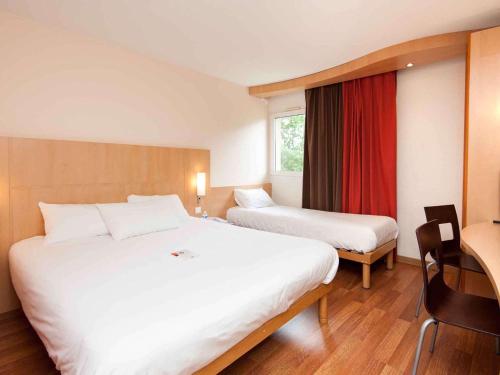 een hotelkamer met 2 bedden en een raam bij ibis Avallon in Magny