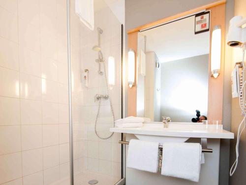 a bathroom with a shower and a sink and a mirror at ibis Avallon in Magny