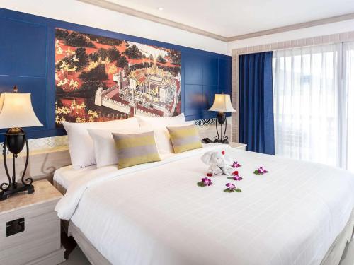 Un dormitorio con una gran cama blanca con flores. en Novotel Phuket Resort en Patong