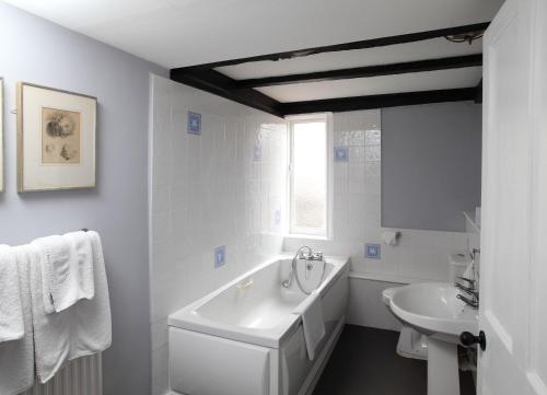a white bathroom with a tub and a sink at Black Lion Hotel in Little Walsingham