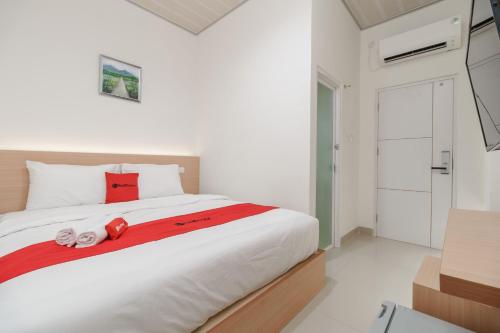 RedDoorz near Jalan Majapahit Lubuk Linggau في Tabahpingin: غرفة نوم بيضاء مع سرير كبير مع وسائد حمراء