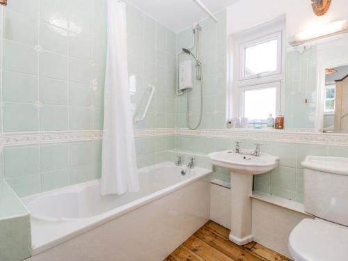 a bathroom with a bath tub and a sink at Oxford House in Minehead