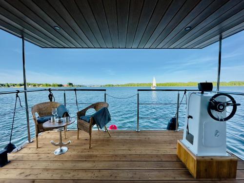 a wooden dock with two chairs and a table on the water at Domki na wodzie - Resort 36 Houseboats in Giżycko