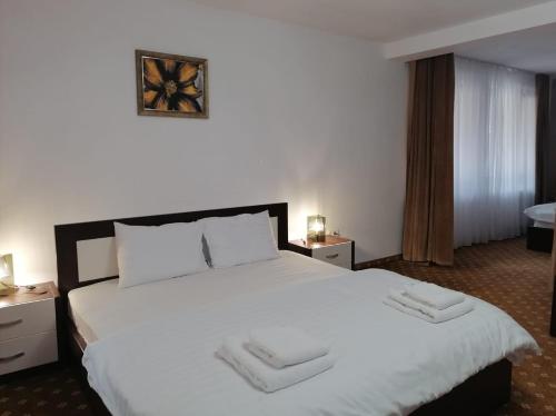 a hotel room with a large bed with white sheets at Pensiunea Perla Codrului in Meziad