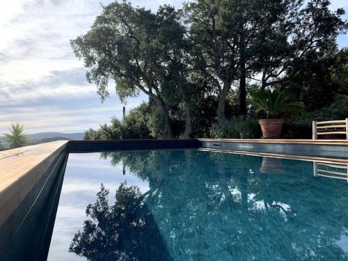 a swimming pool with a reflection in the water at Magnifique villa avec piscine, splendide vue mer. in Porto-Vecchio