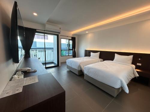 a bedroom with two beds and a flat screen tv at GEEN Hotel Chonburi in Chon Buri