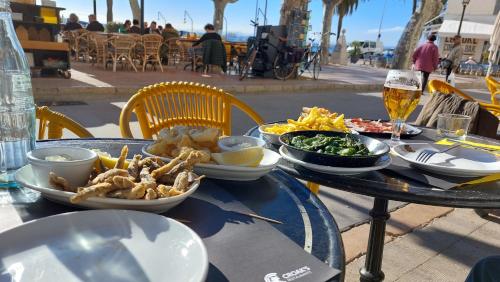 a table with plates of food and a glass of beer at EL GRECO in L'Escala