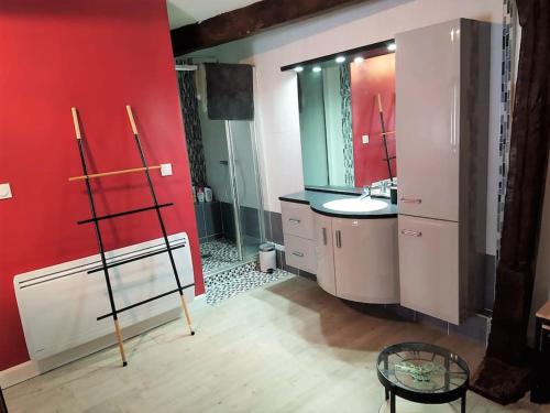 La salle de bains est pourvue d'un lavabo et d'un mur rouge. dans l'établissement Appt de charme en plein cœur historique, à Dives-sur-Mer