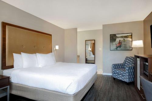 a hotel room with a large bed and a chair at Days Inn by Wyndham Victoria Uptown in Victoria