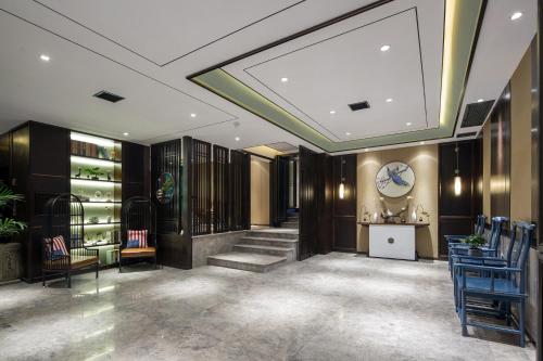 a lobby with a clock on the wall and blue chairs at Morninginn, Phoenix Ancient City Tuojiang in Fenghuang