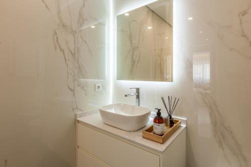 uma casa de banho branca com um lavatório e um espelho em Apartamento Bela Vista - Minho's Guest em Esposende