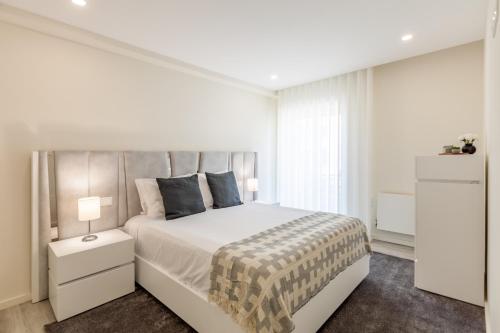una camera da letto bianca con un letto grande e una finestra di Apartamento Bela Vista - Minho's Guest a Esposende
