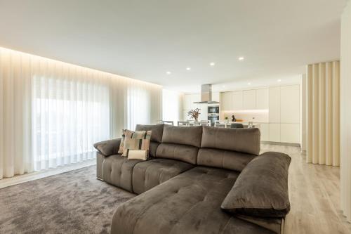 a living room with a brown couch and a kitchen at Apartamento Bela Vista - Minho's Guest in Esposende
