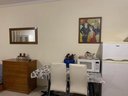 a kitchen with a table with a microwave and a refrigerator at Roses Apartments in Néa Michanióna
