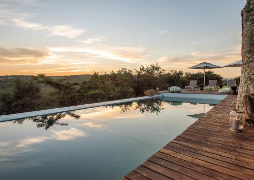 a swimming pool with a wooden deck and the sunset at Tala Collection Game Reserve in Silverton