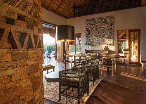 a dining room with tables and chairs and a stone wall at Tala Collection Game Reserve in Silverton