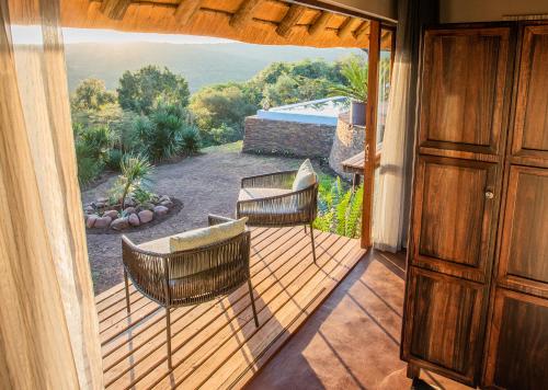 a balcony with two chairs and a view of a yard at Tala Collection Game Reserve in Silverton