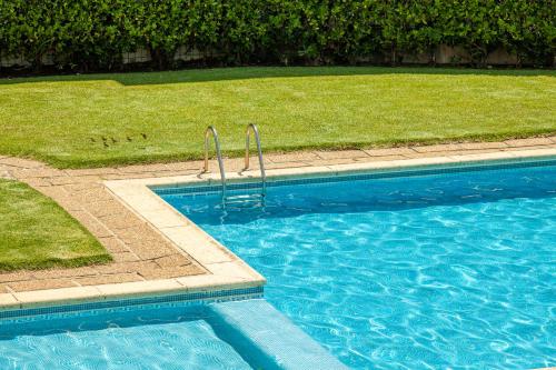 a blue swimming pool with a grassy field next to it at Apartamento Bela Vista - Minho's Guest in Esposende