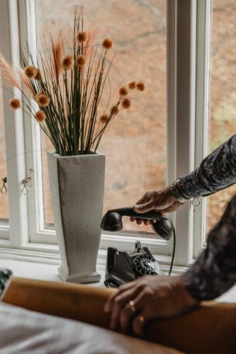 a person standing next to a vase with flowers in a window at Hotel Slottsvillan in Huskvarna
