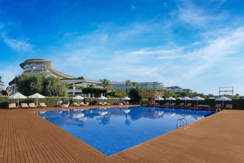 a swimming pool in front of a building with umbrellas at Maxx Royal Belek Golf Resort in Belek
