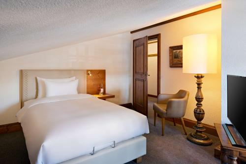 a hotel room with a large bed and a chair at Parkhotel Oberstaufen in Oberstaufen