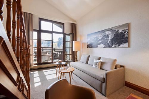a living room with a couch and a large window at Parkhotel Oberstaufen in Oberstaufen