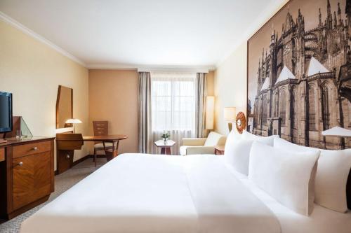 a hotel room with a large white bed and a desk at Lindner Hotel Prague Castle, part of JdV by Hyatt in Prague