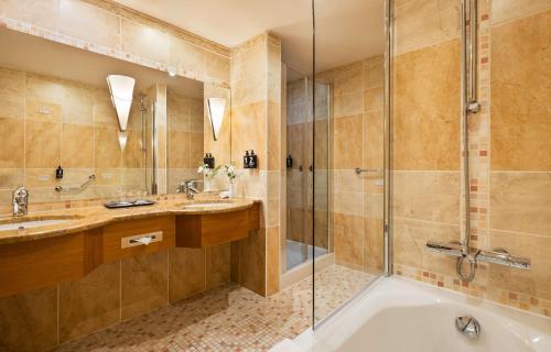 a bathroom with a tub and two sinks and a shower at Lindner Hotel Prague Castle, part of JdV by Hyatt in Prague