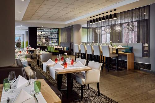 a restaurant with tables and chairs and a bar at Lindner Hotel Cologne City Plaza, part of JdV by Hyatt in Cologne