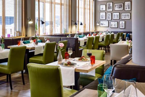 un comedor con mesas y sillas verdes en Lindner Hotel Cologne City Plaza, part of JdV by Hyatt en Colonia