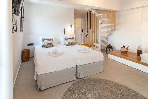 a white bedroom with a large bed and a staircase at Chrissomalli Sofia Studios in Skiathos