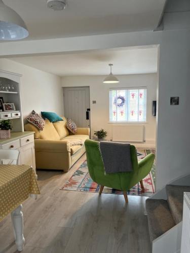 a living room with a green chair and a couch at Corner Cottage with Private Parking Ten Minute Drive from Goodwood in Chichester