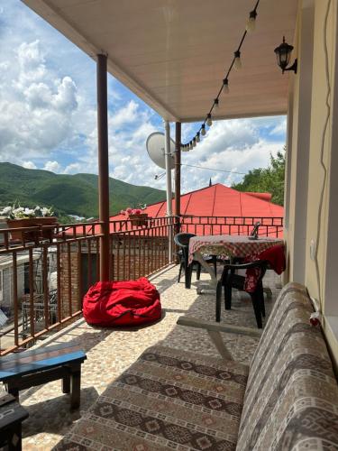 un balcón con una mesa y una bolsa roja. en Shmagdas House Sighnaghi შმაგდას სახლი სიღნაღში en Sighnaghi