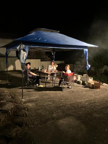 two people sitting at a table under a blue tent at 癒しのwonderland 泉 in Gujo