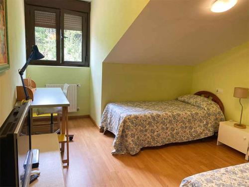 a room with two beds and a desk and a television at "EL TAYUELO" in Posada de Llanes