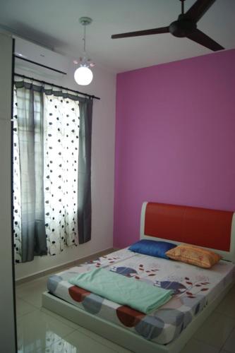een slaapkamer met een bed met een paarse muur bij Anugerah Homestay Islam Ayer Keroh, 4 bilik tidur & 4 bilik air in Melaka
