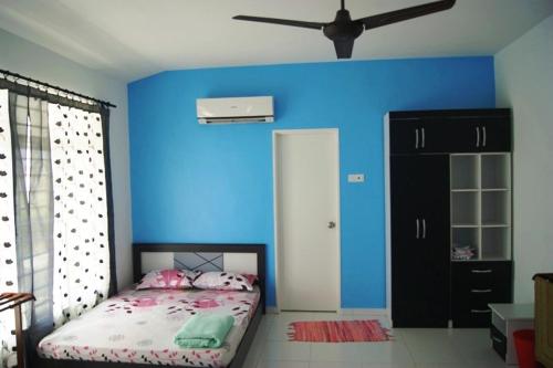 een blauwe kamer met een bed en een zwarte kast bij Anugerah Homestay Islam Ayer Keroh, 4 bilik tidur & 4 bilik air in Melaka