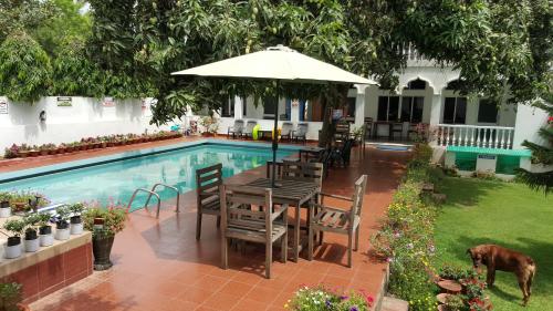 a table with an umbrella next to a swimming pool at Hotel Gandhara in Puri