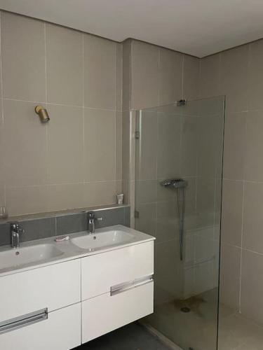 uma casa de banho com um lavatório e uma cabina de duche em vidro. em Appartement De Luxe à Taghazout em Agadir