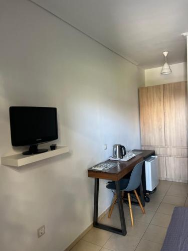 Habitación con escritorio y TV en la pared. en Luxury Studio Artemida, en Artemida