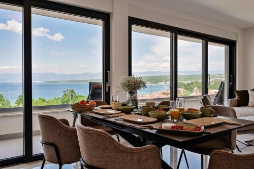 ein Esszimmer mit einem Tisch, Stühlen und Fenstern in der Unterkunft Apartments Sea & Stone in Malinska