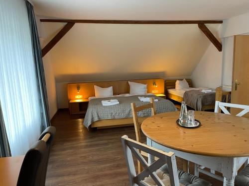 Cette petite chambre comprend deux lits et une table. dans l'établissement Hotel Luther Birke Wittenberg, à Wittemberg