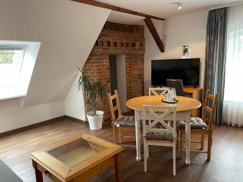 ein Esszimmer mit einem Tisch und einem TV in der Unterkunft Hotel Luther Birke Wittenberg in Lutherstadt Wittenberg