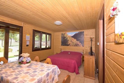 a room with a bed and a table in it at Margherita Camping & Resort in Gressoney-Saint-Jean