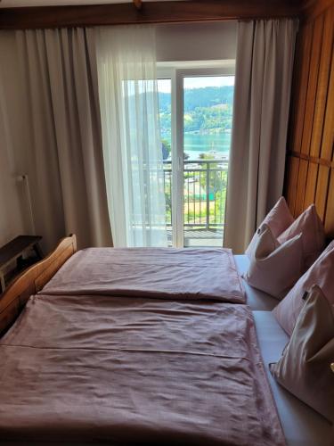 a bedroom with a large bed with a large window at Lucashof Millstättersee in Millstatt