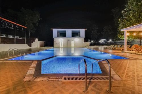 a large swimming pool with blue water at night at Reva Resorts and Holiday Homes in Chittoor